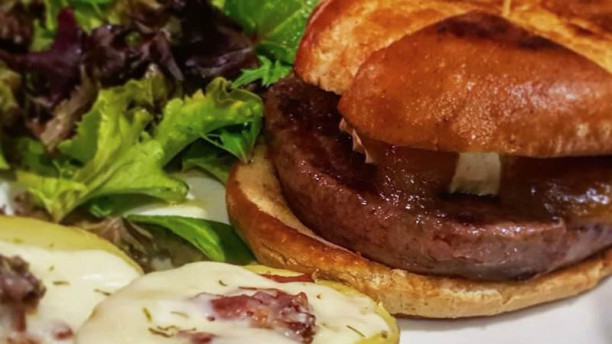 El Pessic Hamburguesa Daniela, con queso brie y cebolla caramelizada, acompañada de una patata al horno con mozzarella y bacon.